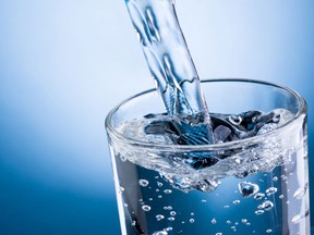 Pouring_water_into_glass_on_blue_background