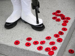 CALGARY, ALBERTA.: NOVEMBER 11, 2011 --  People place their poppies at the foot of the cenotaph next to a member of the Calgary Highlanders in Calgary, Alberta on November 11, 2011 after Remembrance Day services at Central Memorial Park.  (Leah Hennel, Calgary Herald) (For City story by ?)