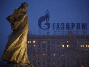 A monument to Ukrainian poet and writer Taras Shevchenko is silhouetted against an apartment building with a sign advertising Russia's natural gas giant Gazprom, in Moscow, Russia, Tuesday, March 4, 2014. Russia's state-controlled natural gas giant Gazprom said Tuesday it will cancel a price discount on gas it sells to Ukraine. Russia had offered the discount in December as part of Russian help for Ukraine. Gazprom also said Ukraine owes it $1.5 billion.