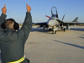 A ground crewman with the 425 Tactical Fighter Squadron in Bagotville, guides a CF-18 Hornet fighter jet before a mission, at Trapani air base in Sicily in this Canadian Forces handout photo dated March 21, 2011. Canada has provided six CF-18 (CF-188) Hornets to enforce the no-fly zone over Libya. Picture taken March 21, 2011.  REUTERS/Corporal Marc-Andre Gaudreault/Canadian Forces Combat Camera/Handout  (ITALY - Tags: MILITARY POLITICS) FOR EDITORIAL USE ONLY. NOT FOR SALE FOR MARKETING OR ADVERTISING CAMPAIGNS. THIS IMAGE HAS BEEN SUPPLIED BY A THIRD PARTY. IT IS DISTRIBUTED, EXACTLY AS RECEIVED BY REUTERS, AS A SERVICE TO CLIENTS