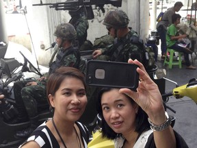 Residents stop to take a photograph of themselves at a military checkpoint in central Bangkok, Tuesday, May 20, 2014. Thailand's army declared martial law in a surprise announcement before dawn Tuesday that it said was aimed at keeping the country stable after six months of sometimes violent political unrest. The military, however, denied a coup d'etat was underway. (AP Photo/Kiko Rosario)