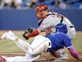 Toronto Blue Jays' Jose Reyes dives into home plate to score as Los Angeles Angels catcher Hank Conger attempts fields a throw during first inning American League baseball action in Toronto on Sunday, May 11, 2014. THE CANADIAN PRESS/Frank Gunn