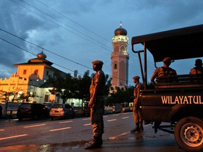 FILE - In this Dec. 31, 2013 file photo, Sharia police officers stand guard at a check point set up to prevent people from celebrating New Year's eve in Banda Aceh, Aceh Province, Indonesia.