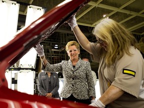 Ontario Premier Kathleen Wynn, left, looks under the hood of a Toyota car as she talks with an employee at the Toyota Motor Manufacturing Canada assembly plant during a campaign stop in Cambridge, Ont., on Tuesday, May 21, 2014.