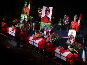 The caskets, left to right, of Const. Dave Joseph Ross, 32, Const. Douglas James Larche, 40, and Const. Fabrice Georges Gevaudan, 45, sit in Wesleyan Celebration Centre during a public visitation in Moncton, N.B. on June 9, 2014.