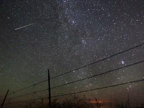 A meteor streaks past the faint band of the Milky Way galaxy