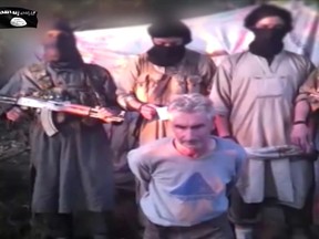 In this still image from video published online Wednesday by a group calling itself Jund Al-Khilafah, or Soldiers of the Caliphate, members of the group stand behind French mountaineer Herve Gourdel just before beheading him. In the video, the men pledge their allegiance to the leader of the Islamic State group, Abu Bakr al-Baghdadi, before killing Gourdel, 55, who they abducted on Sunday.
