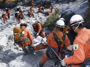 In this Sunday, Sept. 28, 2014 photo released by Tokyo Fire Department, Tokyo Fire Department firefighters carry an injured by Saturday's initial eruption from the summit of Mount Ontake in central Japan. A dozen more bodies were found Wednesday, Oct. 1 near the ash-covered summit of the Japanese volcano as searches resumed amid concern of toxic gasses and another eruption. (AP Photo/Tokyo Fire Department) EDITORIAL USE ONLY