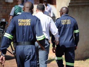 South African forensic investigators walk outside the home of actress and singer Kelly Khumalo in Vosloorus, east of Johannesburg, South Africa, Monday Oct. 27, 2014. Senzo Meyiwa, the captain of the South African national soccer team, was fatally shot at Khumalo's house during an attempted robbery Sunday night as he tried to apprehend the intruders, police and an eyewitness said.
