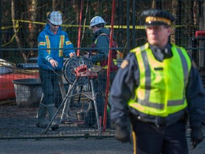 Police protect Kinder Morgan workers as they continue to block protesters of Kinder Morgan's plans to survey pipeline project in Burnaby, B.C., Nov. 23, 2014.