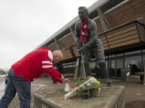 Serge Laflamme lights a candle at a statue of Jean Beliveau Wednesday, December 3, 2014 in Longueuil, Que.. The Montreal Canadiens hockey legend passed away Tuesday, Dec. 2, 2014 at the age of 83. THE CANADIAN PRESS/Ryan Remiorz