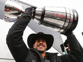 Calgary Stampeders Jon Cornish lifts the Grey Cup as he returns to Calgary, Monday, Dec. 1, 2014, after defeating the Hamilton Tiger-Cats to win the 102nd Grey Cup. THE CANADIAN PRESS/Jeff McIntosh