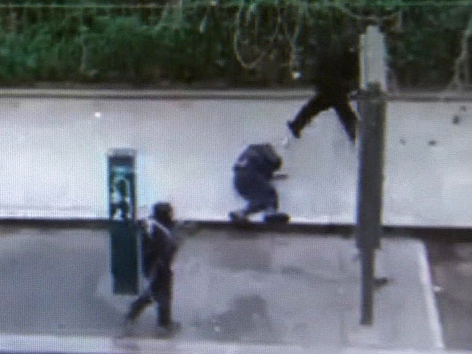  Gunman walk past police officer Ahmed Merabet moments after shooting him at point blank range outside the offices of French satirical newspaper Charlie Hebdo in Paris on Wednesday, Jan. 7, 2015.