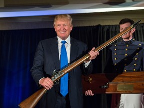 Reality TV host and New York real estate mogul Donald Trump holds up a replica flintlock rifle awarded him by cadets during the Republican Society Patriot Dinner at the Citadel Military College on February 22, 2015 in Charleston, South Carolina.
