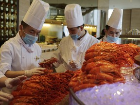 HOLD FOR STORY SLUGGED: CHINA LOBSTER BOOM BY JEFF MCMILLAN - In this Feb. 9, 2015 photo, Chinese chefs prepare Boston lobsters at the Auspicious Garden restaurant in Pangu Seven Star Hotel in Beijing. Every morning at 9, the Auspicious Garden restaurant in Beijing receives 800 lobsters that have just crossed the Pacific aboard a cargo plane. In the evening, hundreds of diners fill the two-story restaurant in the gigantic hotel for a nearly $80 all-you-can-eat buffet with the New England specialty as the main attraction. (AP Photo/Andy Wong)