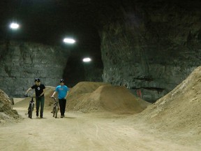 In this Jan. 21, 2015 photo, bike riders Brad Titzer, left, and Derek Fetko walk their bikes during a test run through a new underground bike park in Louisville, KY. The course is built inside an old limestone mine that has become a tourist attraction in Louisville in recent years.