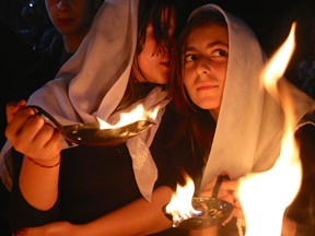 In this Tuesday, April 15, 2015 photo, a Yazidi woman whispers into the ear of her friend as both hold small fires to make a wish for the Yazidi new year, at the holy shrine of Lalish, 57 kilometres north of the militant-held Mosul, Iraq.