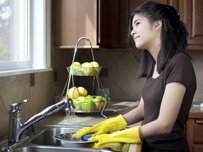 A teen washes dishes at kitchen sink.