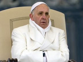 FILE - In this Wednesday, Nov. 27, 2013 file photo Pope Francis tries to keep himself warm as he attends his weekly general audience in St. Peter's Square at the Vatican. Pope Francis released his much-anticipated encyclical 'Laudato Si' (Praise Be), on the environment Thursday, declaring an urgent need for the political and spiritual conversion of global leaders and individuals to dedicate themselves to curbing climate change and ending policies and personal habits that destroy creation. (AP Photo/Alessandra Tarantino, file )