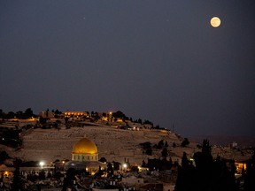 The moon rises over Jerusalem's Old City and the Dome of the Rock seen from the roof restaurant of the Notre Dame hotel.