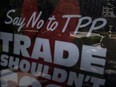 A man is seen reflected, on a bus stop,  in an advertisement protesting the passage of the Trans-Pacific Partnership in Washington, DC on July 23, 2015. Expectations that the Trans-Pacific Partnership (TPP), an accord that would encompass 40 percent of global trade, would be sealed this year increased after US President Barack Obama was last month given fast-track authority by Congress to negotiate such deals. AFP PHOTO/BRENDAN SMIALOWSKIBRENDAN SMIALOWSKI/AFP/Getty Images