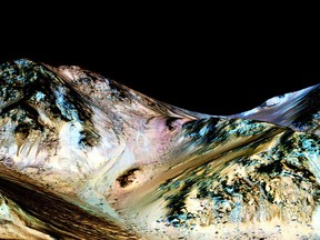 A handout image made available by NASA on September 27, 2015, shows dark, narrow, 100 meter-long streaks called recurring slope lineae flowing downhill on Mars, inferred to have been formed by contemporary flowing water. Recently, planetary scientists detected hydrated salts on these slopes at Hale crater, corroborating their original hypothesis that the streaks are indeed formed by liquid water. The blue color seen upslope of the dark streaks are thought not to be related to their formation, but instead are from the presence of the mineral pyroxene.  AFP PHOTO /NASA/JPL/UNIVERSITY OF ARIZONA   ==RESTRICTED TO EDITORIAL USE - MANDATORY CREDIT "AFP PHOTO /NASA/JPL/UNIVERSITY OF ARIZONA" - NO MARKETING NO ADVERTISING CAMPAIGNS - DISTRIBUTED AS A SERVICE TO CLIENT - AFP IS NOT RESPONSIBLE FOR ANY DIGITAL ALTERATIONS TO THE PICTURE'S EDITORIAL CONTENT, DATE AND LOCATION ==-/AFP/Getty Images