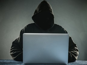Local Input~ A hacker with a hood with laptop. Online network danger. Credit: fotolia