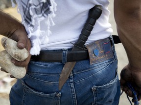 A Palestinian demonstrator has a knife in his belt and rocks in his hand during clashes with Israeli troops, near Ramallah, West Bank, Sunday, Oct. 18, 2015.