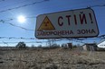 A sign reading "Stop, Forbidden Zone" hangs on a barbed wire fence that surrounds the Chernobyl nuclear power plant.