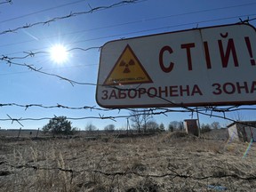 A sign reading "Stop, Forbidden Zone" hangs on a barbed wire fence that surrounds the Chernobyl nuclear power plant.