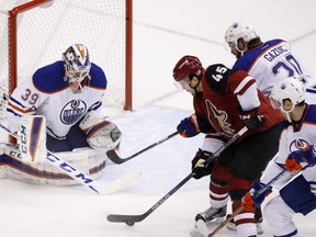 Arizona Coyotes' Stefan Elliott is on his way to flipping the puck past Edmonton Oilers goalie Anders Nilsson for a goal as Oilers' Mark Fayne and Luke Gazdic defend during the second period  during game Thursday in Glendale, Ariz.