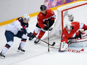 Canada goaltender Carey Price blocks a shot at the goal by USA forward Zach Parise as Canada defenseman Alex Pietrangelo skates into help protect the goal during the men's semifinal ice hockey game at the 2014 Winter Olympics.