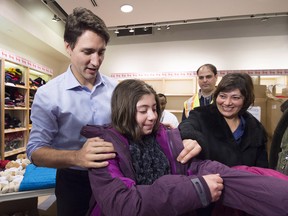 Canadian Prime Minister Justin Trudeau gives newly-arrived Syrian refugee  a winter jacket at Pearson International airport, in Toronto, on Friday, Dec. 11, 2015.