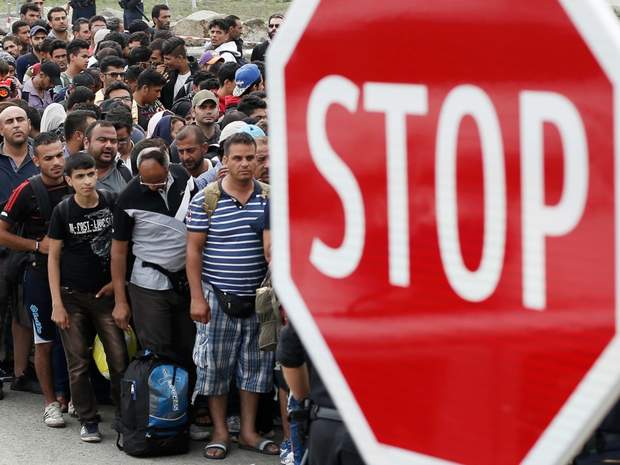Migrants wait for buses to Vienna close to a stop sign at the border crossing point on September 15, 2015 in Nickelsdorf, Austria. 