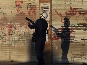 A riot policeman fires tear gas toward Bahraini anti-government protesters in Daih, Bahrain, on Saturday, Feb. 13, 2016. Layers of anti-government graffiti are seen on shuttered storefronts as businesses in opposition areas nationwide observed a general strike in the run-up to Sunday's fifth anniversary of Bahrain's Arab Spring uprising. (AP Photo/Hasan Jamali)