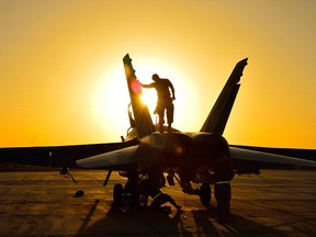 Ground crew perform post flight checks on a Canadian CF-18 fighter jet in Kuwait after a sortie over Iraq during Operation IMPACT in November, 2014.