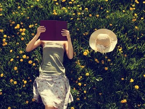 Girl lying in grass, reading a book.