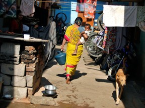 A woman holds her child as she carries a pot of drinking water in a slum area in Bangalore, India.