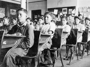 An archival photo of residential school students in a typical classroom.