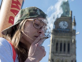 A woman smokes a joint during the annual 420 marijuana rally on Parliament hill on Wednesday, April 20, 2016 in Ottawa.