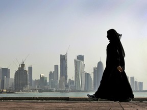 A Qatari woman walks in front of the city skyline in Doha, Qatar. A Dutch woman held in Qatar for nearly three months after telling police she had been raped was released Monday.