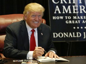 Republican presidential hopeful Donald Trump signs copies of his new book "Crippled America: How to Make America Great Again" during an event at Trump Tower on November 3, 2015 in New York.