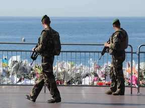 Soldiers pass by the new makeshift memorial in tribute to the victims of the deadly Bastille Day attack at the Promenade des Anglais on July 19, 2016 in Nice