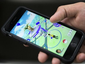 A man plays Pokemon Go game on a smartphone on July 22, 2016 in Tokyo, Japan. Police say a woman playing Pokemon Go in a parking lot north of Toronto was nearly hit by a driver who was also playing the wildly popular smartphone game