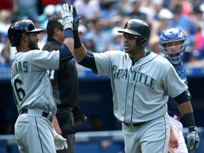 Nelson Cruz, right, of the Seattle Mariners is congratulated by teammate Luis Sardinas after hitting a three-run homer in the eighth inning against the Blue Jays at Rogers Centre in Toronto on Saturday.