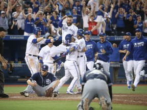 Devon Travis of the Toronto Blue Jays is congratulated by Edwin Encarnacion as Kevin Pillar leaps in the air after their game-winning run scored on a wild pitch in the 12th inning against the San Diego Padres on Tuesday.