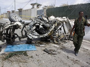 Somali soldier stand near the wreckage of a car bomb outside the UN's office in Mogadishu, Somalia, Tuesday, July 26, 2016.