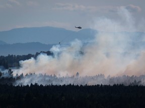 A helicopter prepares to drop water on a fire burning at Burns Bog in Delta, B.C., on Sunday, July 3.