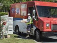 A Canada Post employee fills a community mail box in Dartmouth, N.S.