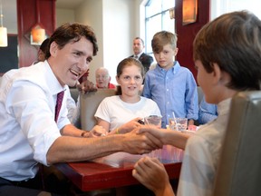 Prime Minister Justin Trudeau shakes hands with some children in a restaurant in Aylmer, Que., on July 20.